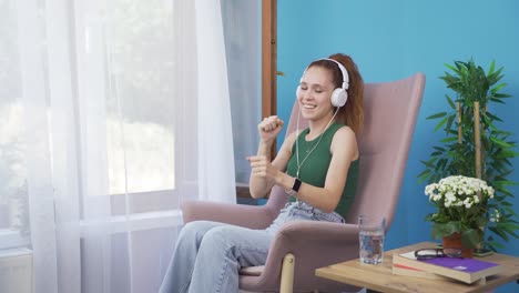 Woman-looking-out-the-window-and-listening-to-music-with-headphones.